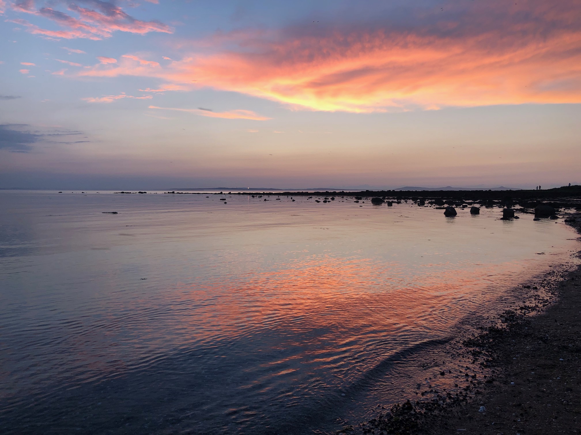A photo taken at Longniddry beach in East Lothian - a perfect spot for reflection, with vibrant sunset colors reflected in calm waters